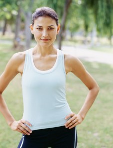portrait of a young woman standing with arms akimbo in a park